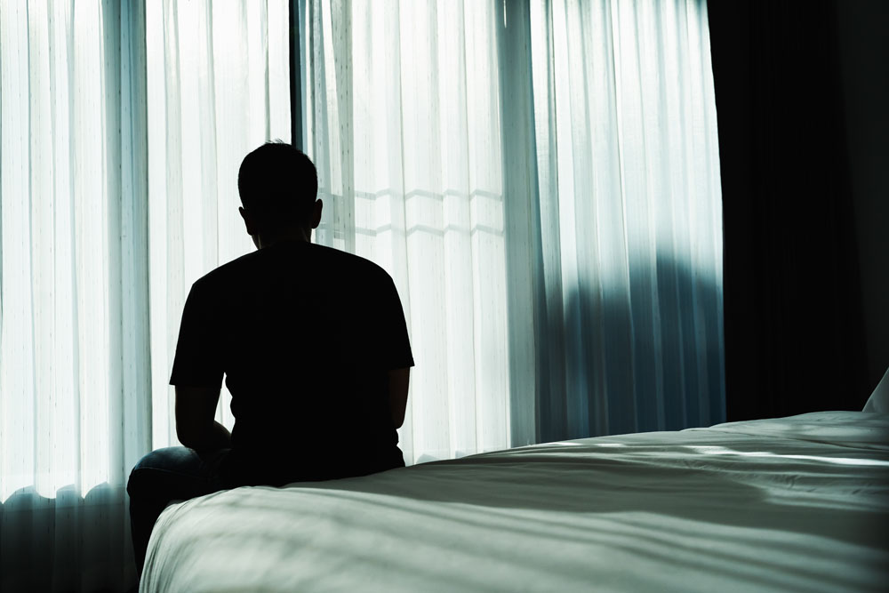 Man sitting alone on the corner of the bed